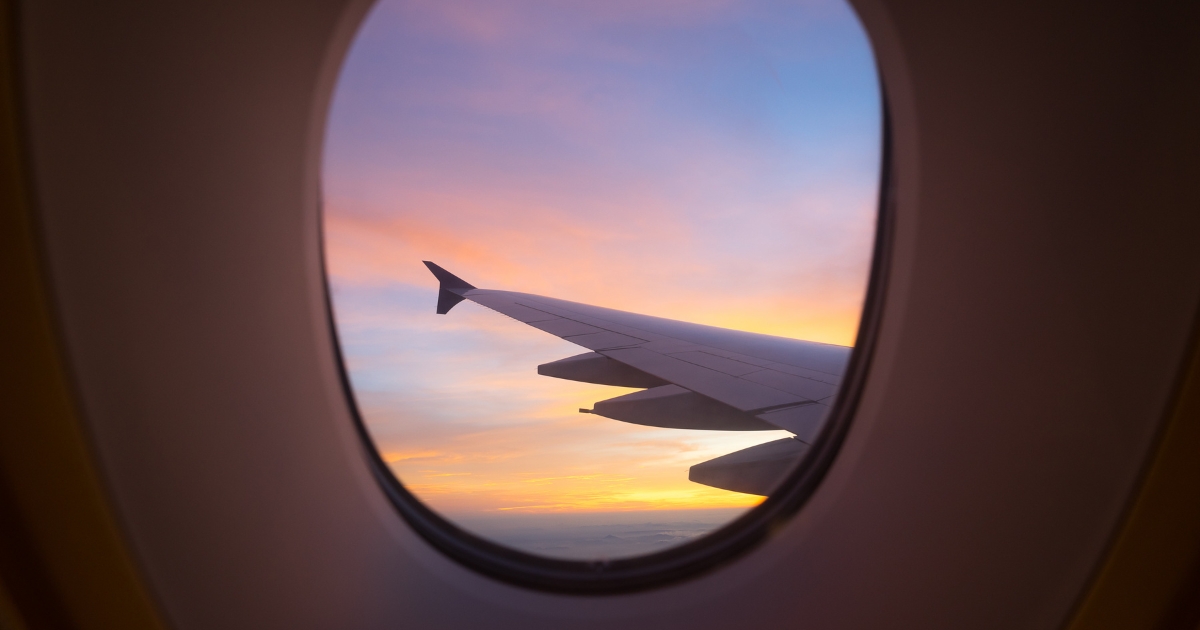 View of an airplane wing through a window at sunset